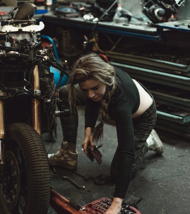 beautiful girl with long hair in the garage repairing a motorcycle